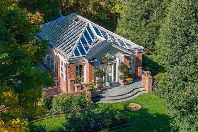 view of front of house featuring metal roof, a patio, brick siding, and a front yard