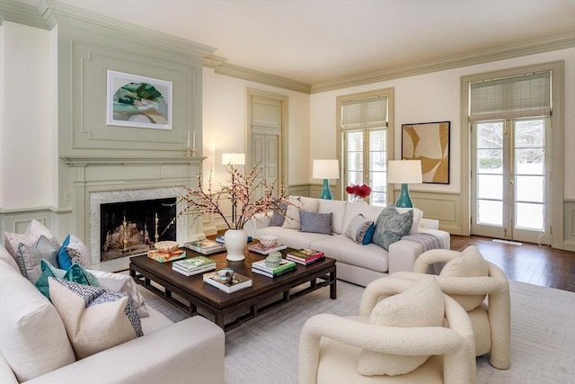 living room with a premium fireplace, a wainscoted wall, wood finished floors, and ornamental molding