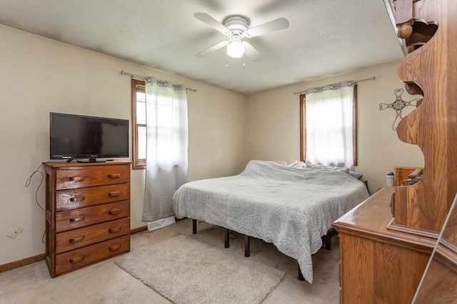 bedroom featuring multiple windows, light carpet, ceiling fan, and baseboards