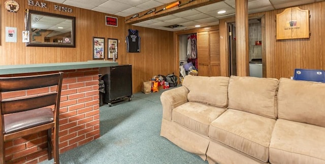 carpeted living area featuring a drop ceiling and wooden walls