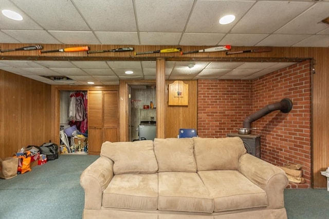 carpeted living room with wooden walls, a wood stove, a drop ceiling, recessed lighting, and washer / dryer