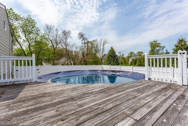 view of swimming pool featuring a wooden deck and fence