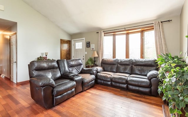 living area with hardwood / wood-style floors, vaulted ceiling, and baseboards