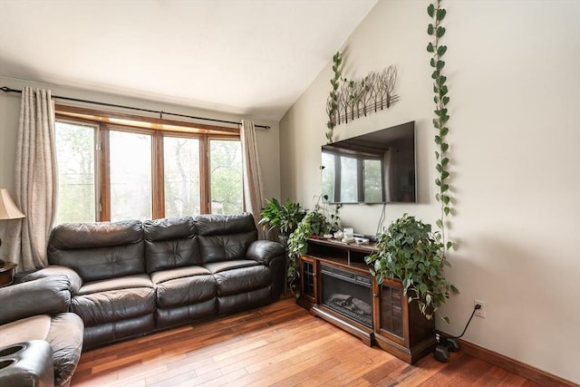 living room featuring light wood-type flooring, vaulted ceiling, healthy amount of natural light, and baseboards