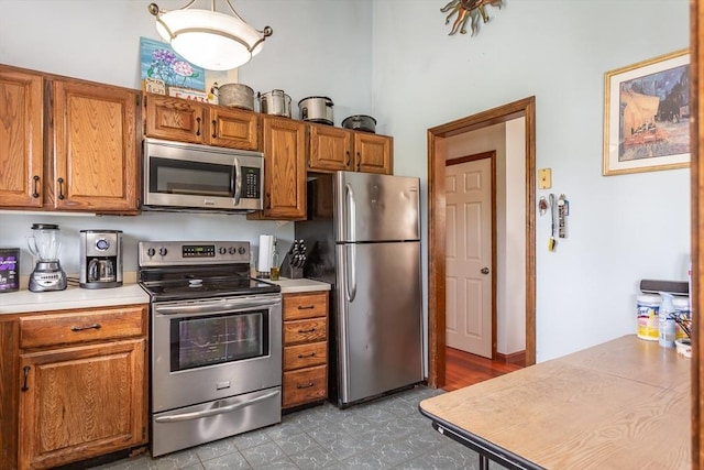 kitchen with appliances with stainless steel finishes, brown cabinets, light countertops, and tile patterned floors