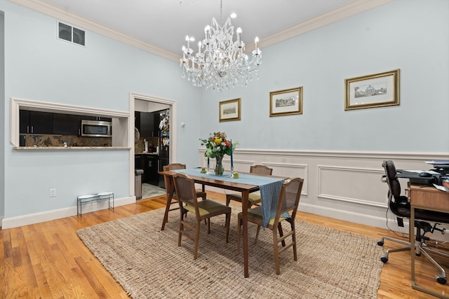 dining room featuring ornamental molding, light hardwood / wood-style floors, and a chandelier