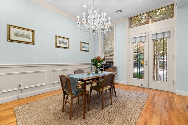 dining room with ornamental molding, a chandelier, and light hardwood / wood-style flooring