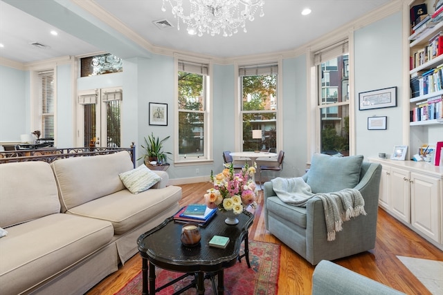 living room featuring light wood-type flooring, ornamental molding, and an inviting chandelier