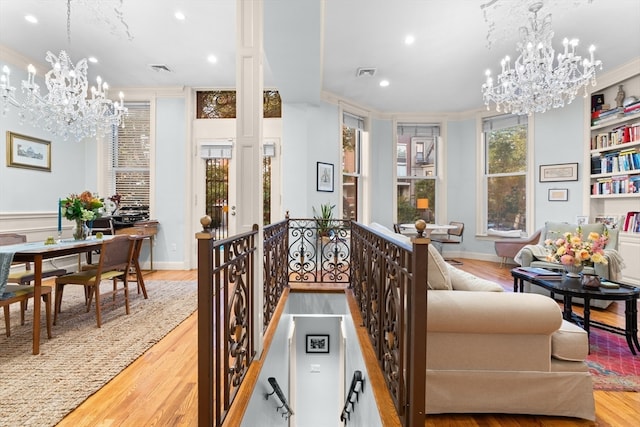 living room featuring light wood-type flooring, a chandelier, and crown molding