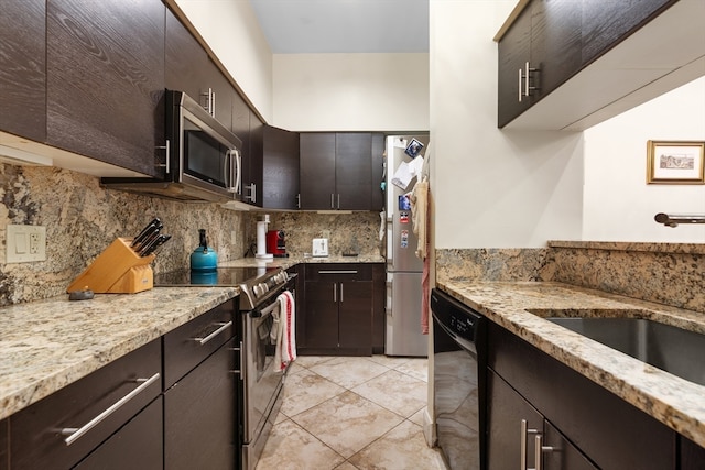 kitchen featuring dark brown cabinetry, tasteful backsplash, stainless steel appliances, and light stone counters