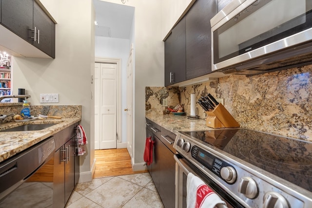 kitchen with light stone counters, sink, decorative backsplash, stainless steel appliances, and light tile patterned floors