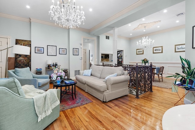 living room featuring ornamental molding, an inviting chandelier, and light hardwood / wood-style flooring