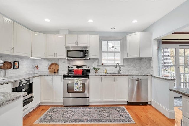 kitchen with appliances with stainless steel finishes, a sink, white cabinets, and recessed lighting