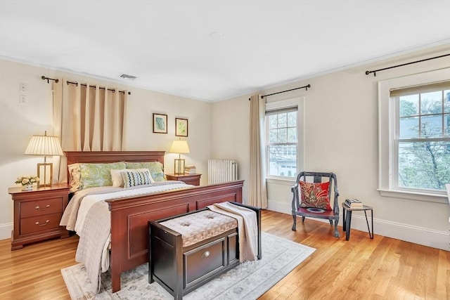 bedroom with light wood-style floors, baseboards, and crown molding