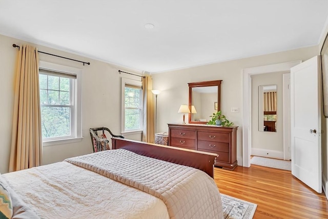 bedroom with light wood-style floors, ornamental molding, and baseboards