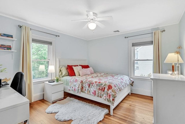 bedroom with crown molding, light wood-style flooring, baseboards, ceiling fan, and a desk