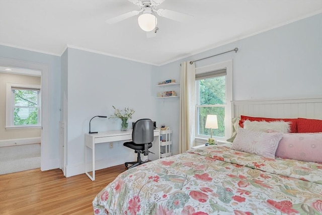bedroom featuring light wood-style flooring, multiple windows, ornamental molding, ceiling fan, and an office area