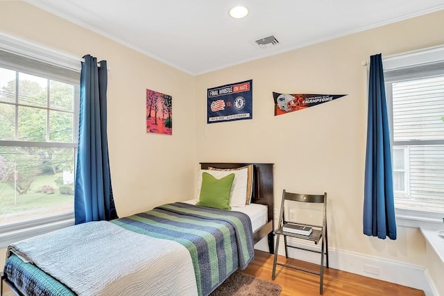 bedroom featuring wood finished floors and ornamental molding
