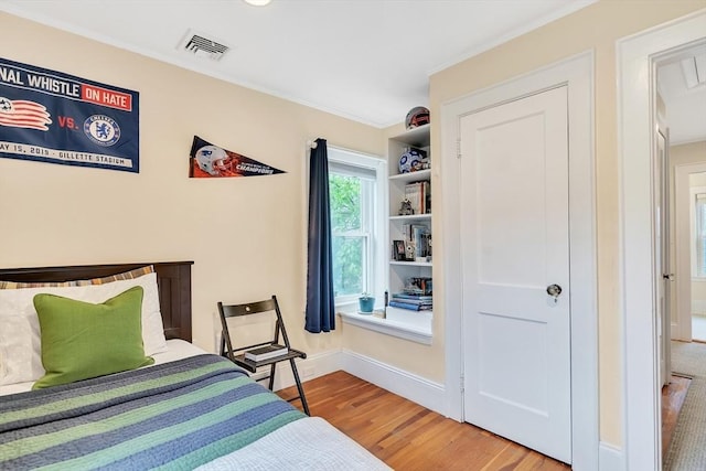 bedroom with wood finished floors, crown molding, and baseboards