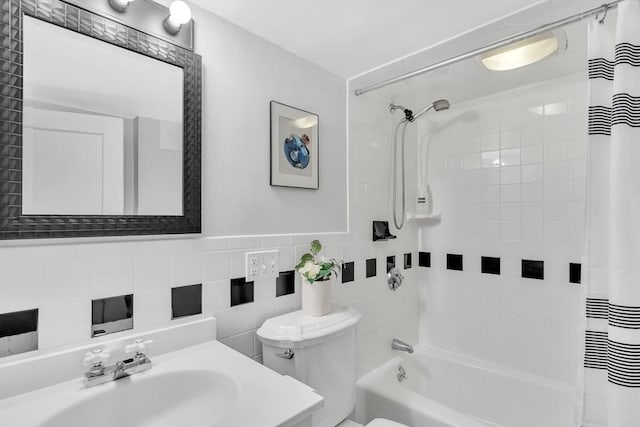 full bath with a sink, shower / bath combo with shower curtain, toilet, and tile walls