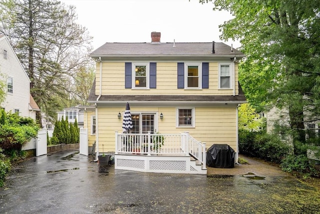 back of house with a chimney and a deck