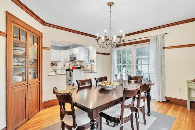 dining space featuring a chandelier, light wood-type flooring, crown molding, and baseboards
