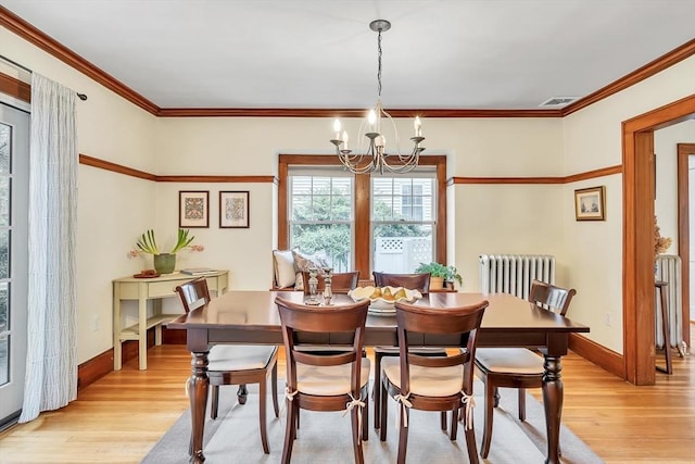 dining area featuring a chandelier, radiator heating unit, light wood-type flooring, baseboards, and crown molding