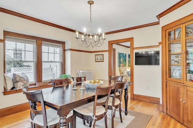 dining area with radiator heating unit, light wood-style flooring, a chandelier, crown molding, and baseboards