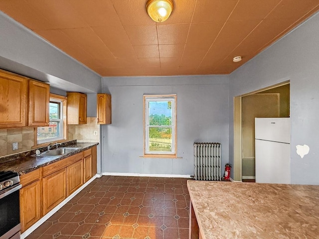 19 High St, Lynn, MA 01902 - kitchen with freestanding refrigerator, radiator heating unit, plenty of natural light, and brown cabinetry