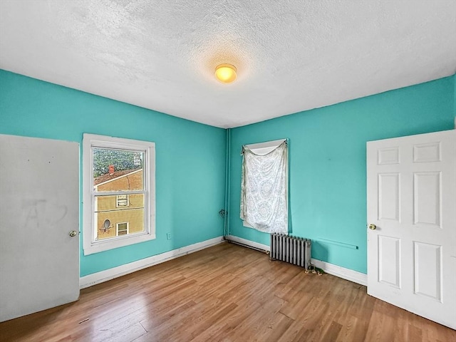 19 High St, Lynn, MA 01902 - empty room featuring radiator heating unit, wood finished floors, and a textured ceiling