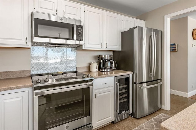 kitchen with light countertops, beverage cooler, appliances with stainless steel finishes, and white cabinetry