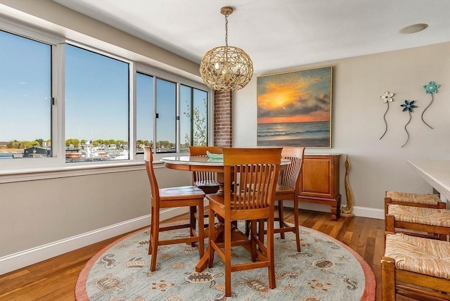 dining space featuring baseboards, wood finished floors, and a notable chandelier