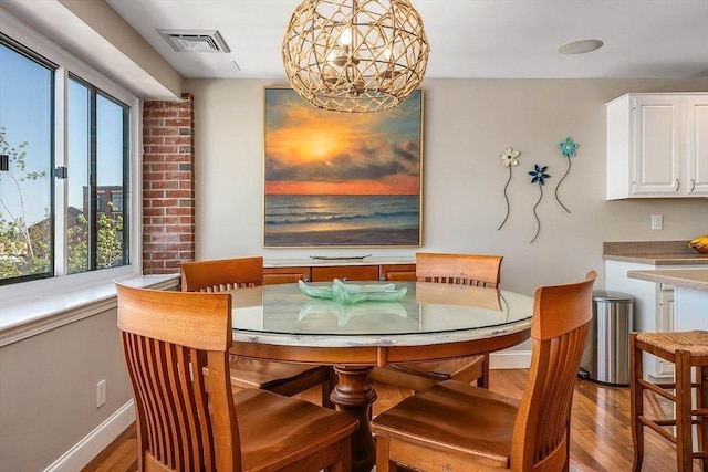 dining space featuring visible vents, light wood-style floors, baseboards, and a notable chandelier