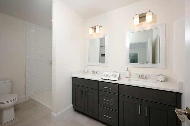 bathroom featuring tile flooring, vanity with extensive cabinet space, dual sinks, a tile shower, and toilet