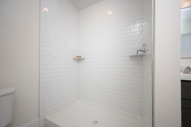 bathroom with vanity, toilet, and a tile shower