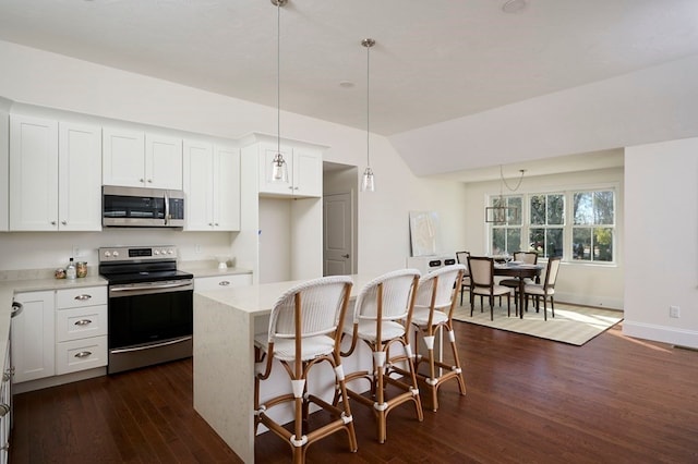 kitchen featuring appliances with stainless steel finishes, dark wood-type flooring, white cabinets, and hanging light fixtures