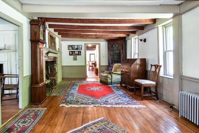 79 Nobscot Rd, Sudbury, MA 01776 - living area featuring a fireplace with flush hearth, radiator heating unit, wainscoting, wood-type flooring, and beamed ceiling
