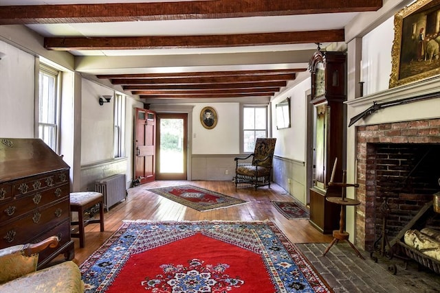 79 Nobscot Rd, Sudbury, MA 01776 - entrance foyer featuring radiator, hardwood / wood-style flooring, beamed ceiling, wainscoting, and a brick fireplace