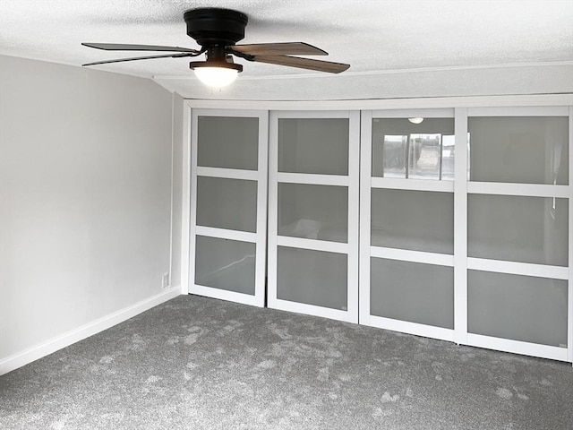 spare room featuring ceiling fan, a textured ceiling, and dark colored carpet