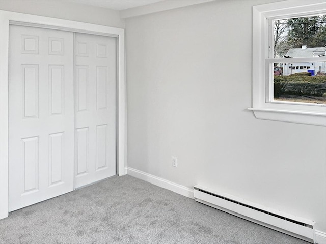 unfurnished bedroom featuring light carpet, baseboard heating, and a closet