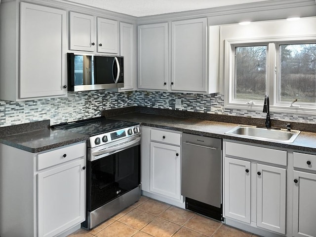 kitchen featuring white cabinetry, appliances with stainless steel finishes, backsplash, light tile patterned flooring, and sink