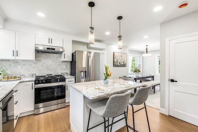 kitchen featuring appliances with stainless steel finishes, under cabinet range hood, light wood-style flooring, backsplash, and recessed lighting
