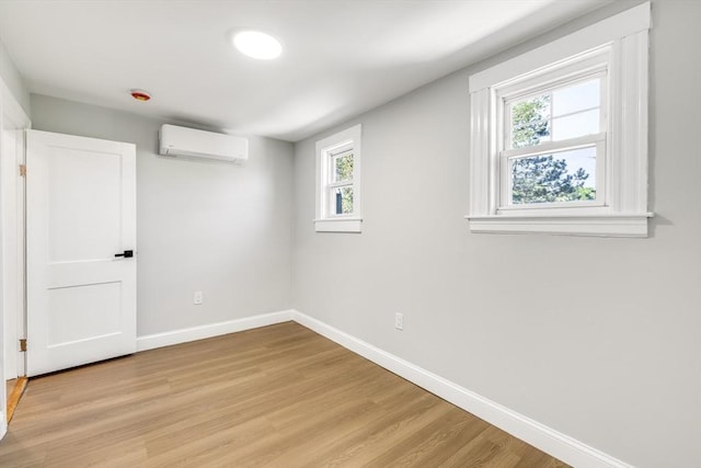 bonus room with a wall unit AC, baseboards, healthy amount of natural light, and light wood-style flooring