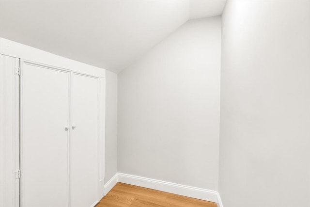 unfurnished bedroom featuring vaulted ceiling, light wood-style floors, and baseboards