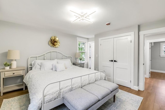 bedroom with wood finished floors, a closet, and baseboards