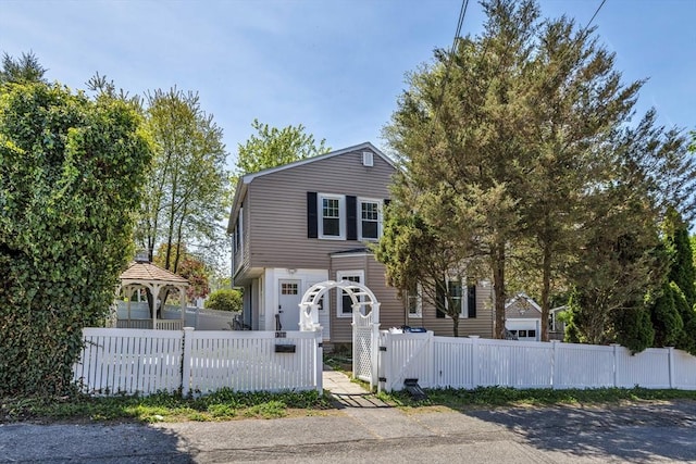 colonial inspired home featuring a gazebo, a fenced front yard, and a gate