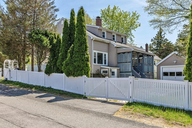 view of front of house with a fenced front yard, an outbuilding, a garage, a chimney, and a gate