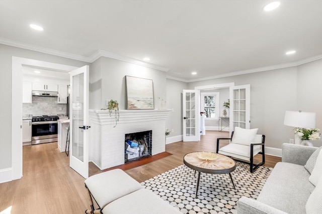 living area featuring french doors, light wood-style floors, recessed lighting, ornamental molding, and a brick fireplace