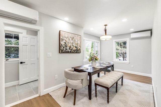 dining area with an AC wall unit, light wood-style flooring, baseboards, and recessed lighting