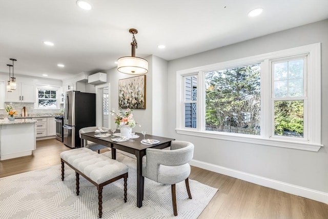 dining space with an AC wall unit, baseboards, light wood finished floors, and recessed lighting